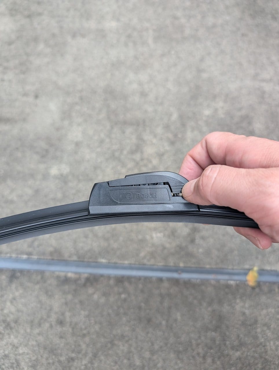 BOSCHエアロツインのアダプター端にあるツメを親指で押しているところ